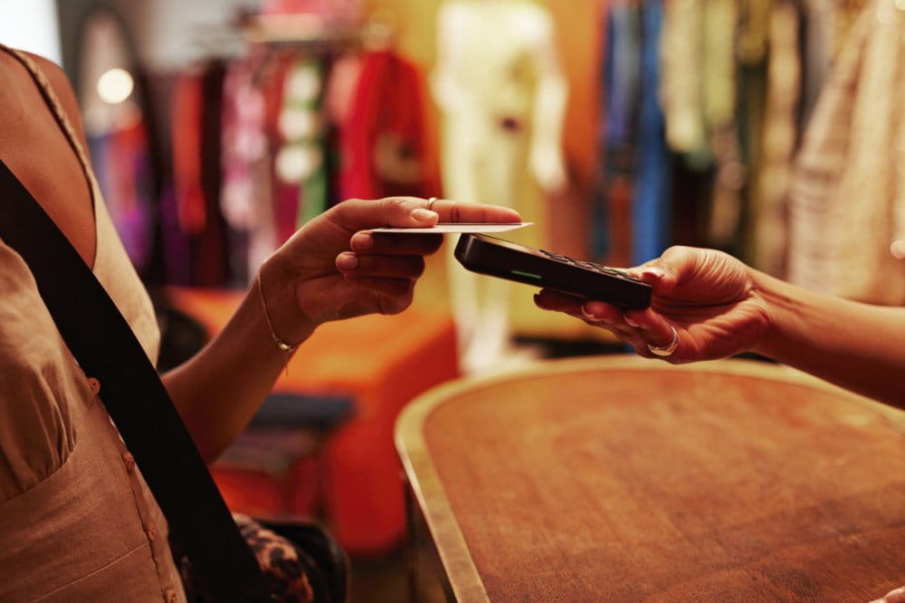 Person utfører en kontaktfri betaling med et bankkort ved en betalingsterminal i en butikk.