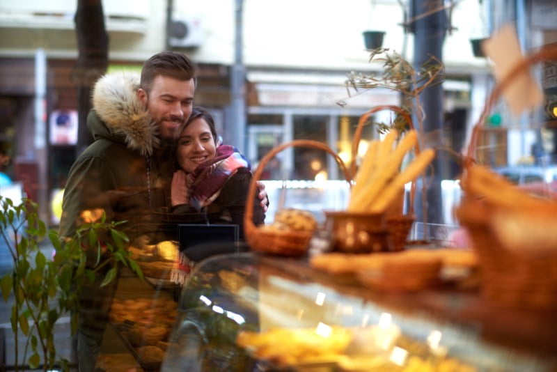 Smilende par koser seg i et bakeri, en stemningsfull scene med varme smil og appetittvekkende bakverk