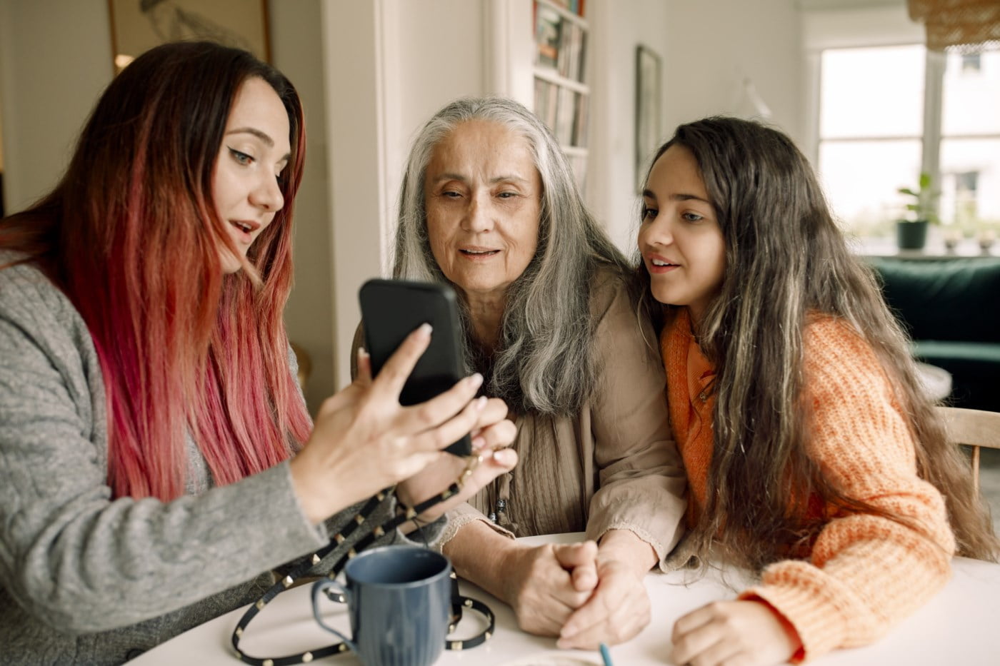 mor, datter og barnebarn ser på mobil
