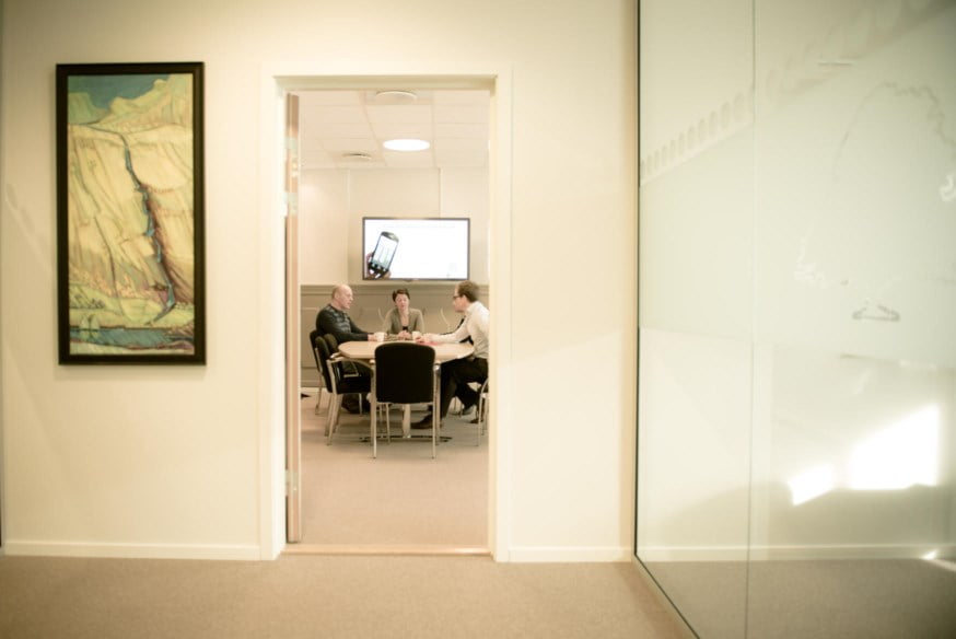 Person ser inn på møterom der personer har møte. foto